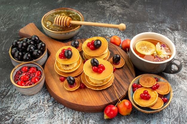 Vista de cerca del desayuno con tortitas de frutas y té servido con miel y cerezas