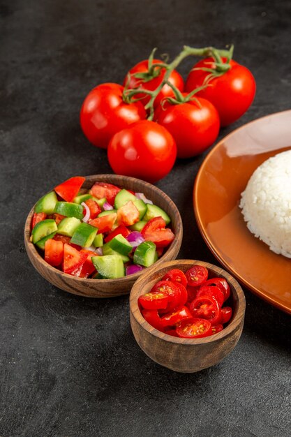 Vista de cerca de diferentes tipos de verduras y arroz en una placa marrón en la oscuridad