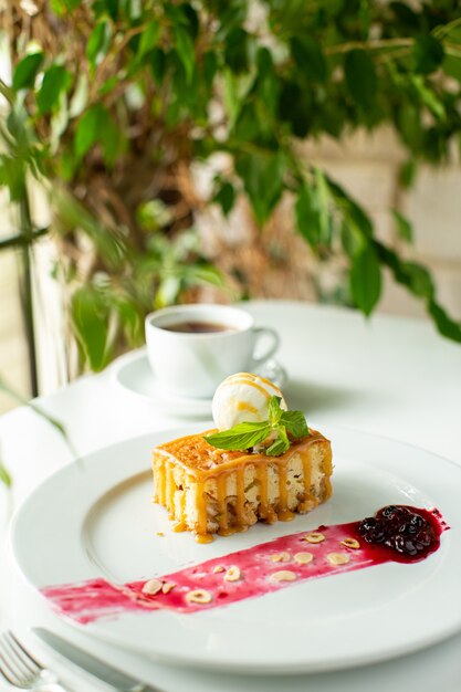 Una vista de cerca frontal pequeño pastel diseñado delicioso dentro de un plato blanco sobre el escritorio blanco