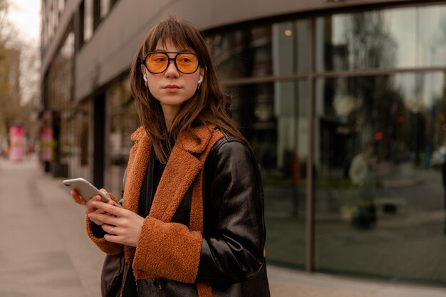 Vista de cerca de una hermosa mujer listando música con gafas de sol