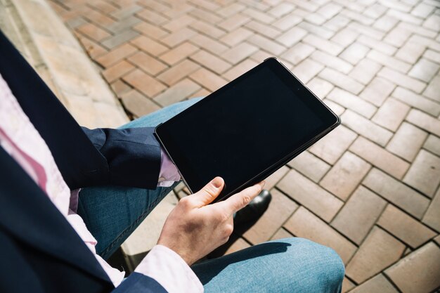 Vista de cerca de hombre de negocios usando tableta al aire libre