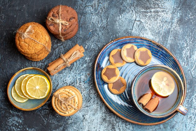 Vista de cerca de la hora del té con varias galletas y mano sosteniendo una taza de té negro