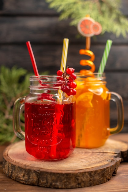 Vista de cerca de jugos de frutas frescas en vasos servidos con tubos sobre una tabla de cortar de madera