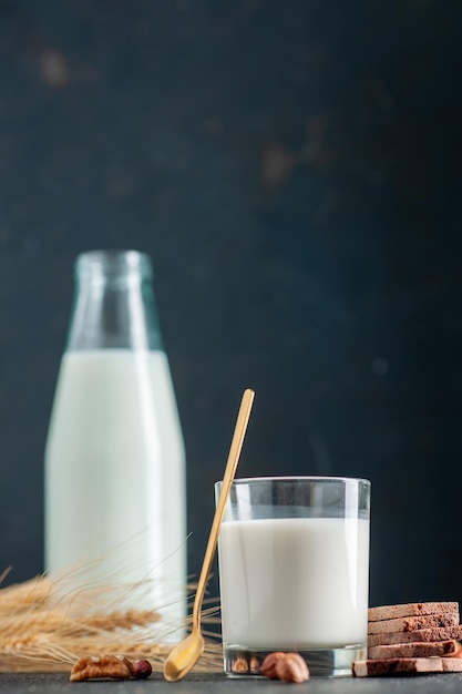 Foto gratuita vista de cerca de una leche fresca en vidrio y botella de galletas de chocolate cuchara dorada cacahuetes nueces sobre superficie negra