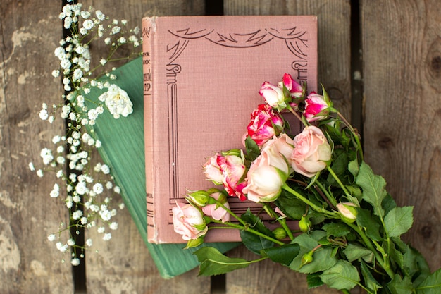 Una vista de cerca de libros y rosas en el piso de madera marrón