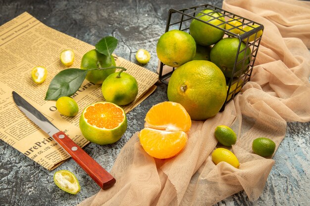 Vista de cerca de limones frescos en una canasta negra caído sobre una toalla, un cuchillo y un periódico en la mesa gris