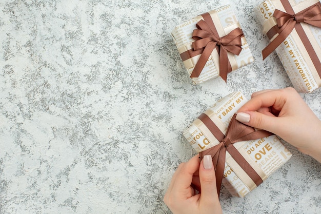 Foto gratuita vista de cerca de la mano que sostiene una de las cajas de regalo bellamente empaquetadas en el lado izquierdo sobre fondo de hielo