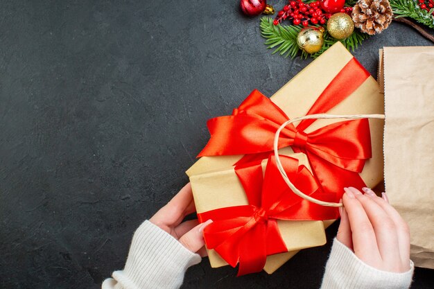 Vista de cerca de la mano sacando una hermosa caja de regalo de una bolsa sobre fondo negro