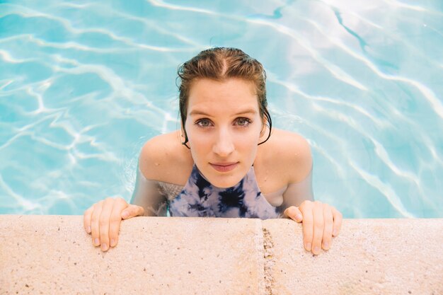 Vista de cerca de mujer joven por el borde de la piscina