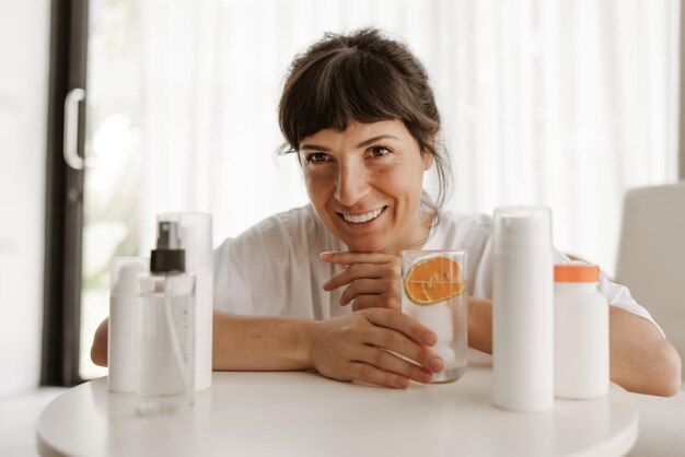 Vista de cerca de una mujer sonriente con productos para limpiar la piel