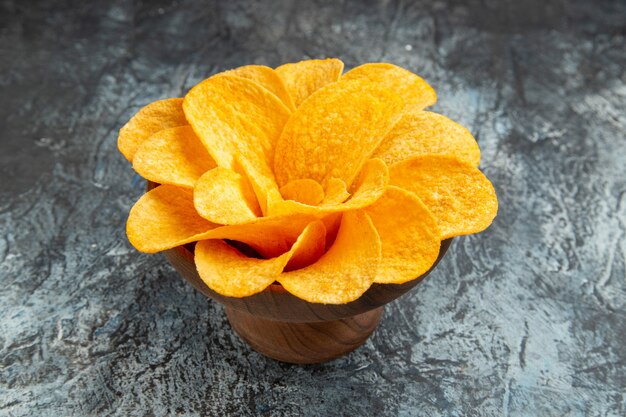 Vista de cerca de papas fritas decoradas con forma de flor en un recipiente marrón sobre mesa gris