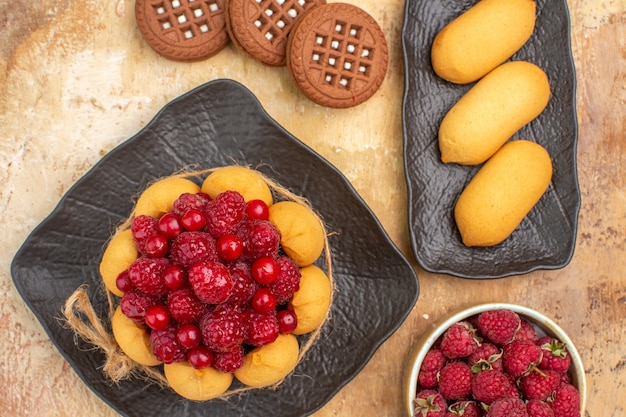 Vista de cerca de un pastel de regalo y galletas en placa marrón sobre tabla de colores mezclados