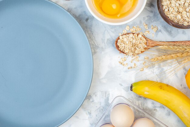 Vista de cerca del plato vacío y los ingredientes para los alimentos saludables sobre fondo azul blanco