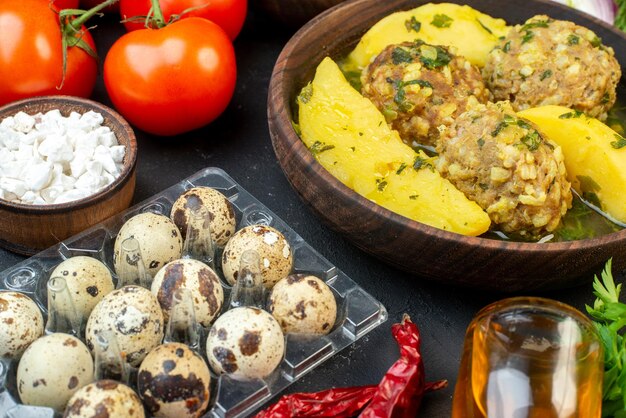 Vista de cerca de la sabrosa comida de albóndigas, tomates verdes, huevos, sal, botella de aceite caída sobre fondo negro