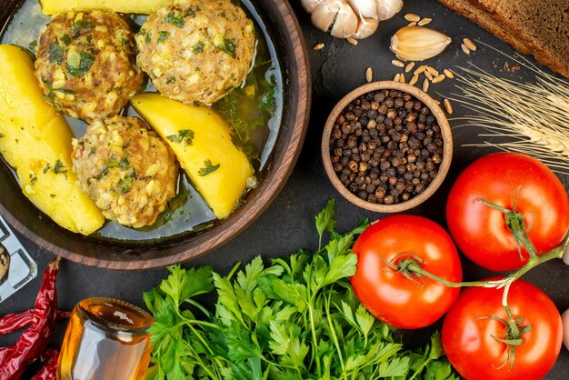 Vista de cerca de la sabrosa comida de albóndigas verduras frescas huevos pimiento verde picos de botella de aceite caídos sobre fondo negro