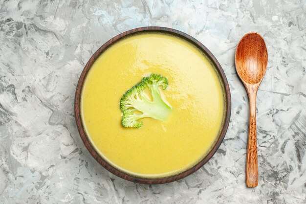 Vista de cerca de la sopa cremosa de brócoli en un recipiente marrón y una cuchara sobre la mesa gris