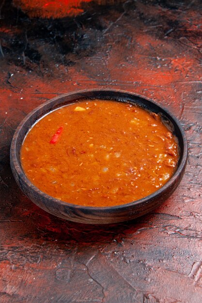 Foto gratuita vista de cerca de la sopa de tomate en un recipiente marrón sobre la mesa de colores mezclados