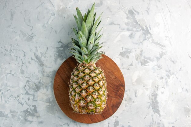 Vista de cerca de toda la piña dorada fresca en la tabla de cortar sobre la superficie de mármol