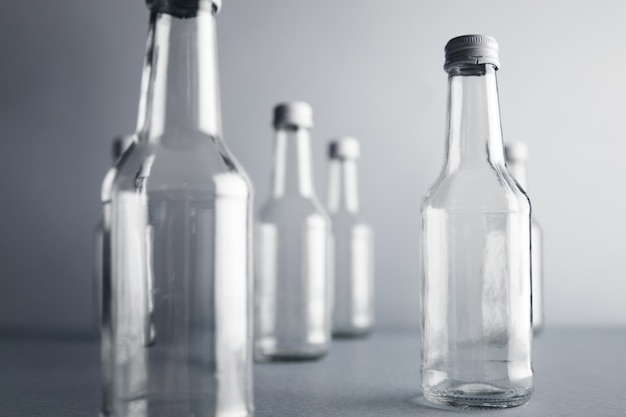 Vista cercana de botellas de vidrio vacías transparentes sin etiqueta para bebidas frías y bebidas