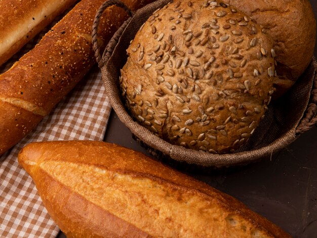 Vista cercana de la cesta de mazorcas sembradas y clásicas con baguettes sobre fondo marrón