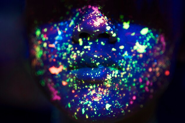 Vista cercana de colorido maquillaje fluorescente en la cara