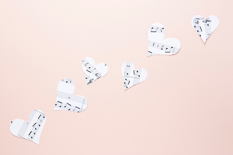 Foto gratuito vista cercana de corazones con notas musicales sobre fondo liso