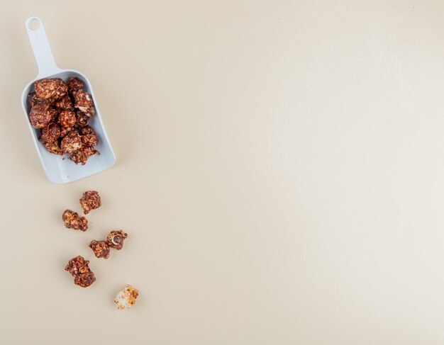 Vista cercana de una cucharada de palomitas de chocolate en el lado izquierdo y fondo blanco con espacio de copia