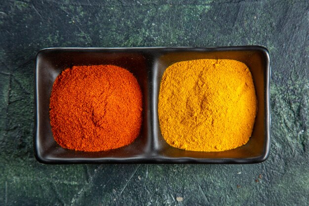 Vista cercana de cuencos de especias con pimiento rojo y jengibre amarillo en la superficie de colores mezclados con espacio libre