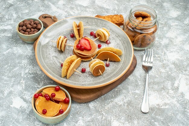 Vista cercana de deliciosos panqueques en la tabla de cortar galletas de chocolate galletas sobre fondo azul