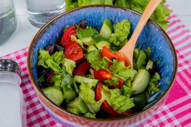 Vista cercana de ensalada de verduras con sal sobre tela escocesa