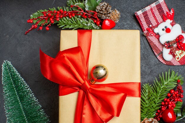 Vista cercana del estado de ánimo navideño con hermosos regalos con cinta en forma de arco y accesorios de decoración de ramas de abeto calcetín de Navidad sobre un fondo oscuro