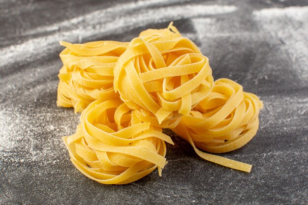 Vista cercana frontal en forma de pasta italiana en forma de flor cruda y amarilla en el escritorio gris