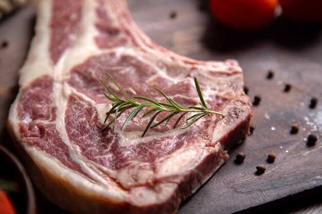 Foto gratuita vista cercana frontal rebanada de carne cruda con tomates rojos frescos en la superficie de madera