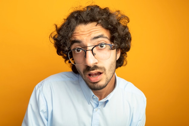 Vista cercana de joven guapo con gafas aislado en la pared naranja