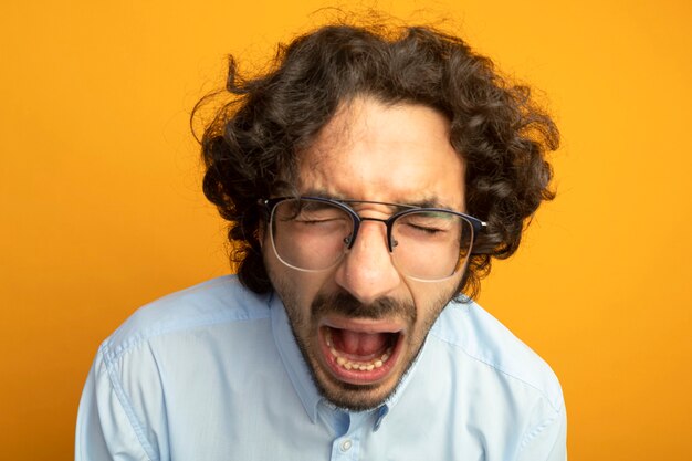 Vista cercana de joven guapo con gafas aislado en la pared naranja