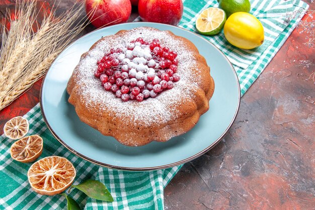 Vista cercana de lado un pastel un pastel con grosellas rojas azúcar en polvo limones manzanas sobre el mantel