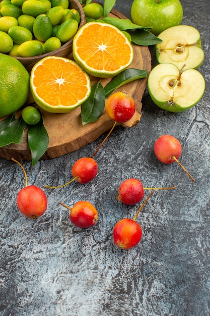 Vista cercana lateral frutas las apetitosas mandarinas manzanas cerezas en el tablero