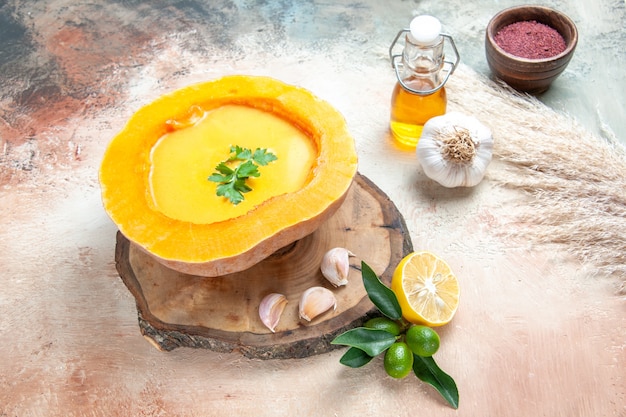 Vista cercana lateral sopa sopa de calabaza con hierbas ajo limón botella de aceite de especias
