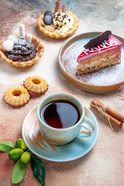 Vista cercana lateral una taza de té una taza de té cupcakes galletas pastel de canela cítricos