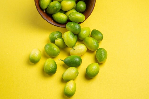 Vista cercana lateral tazón de frutas verdes de las apetitosas frutas verdes sobre la superficie amarilla