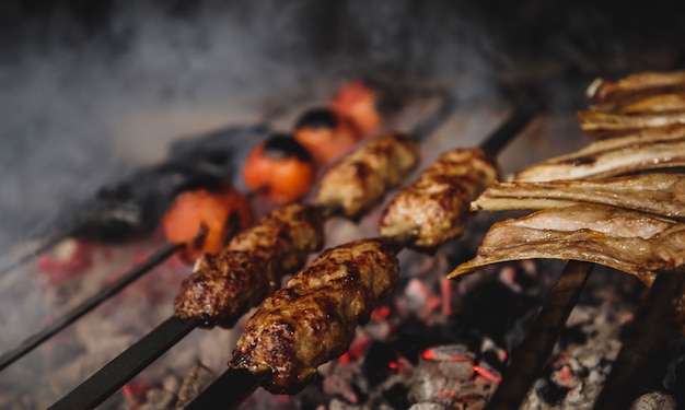 Vista cercana de lula kebab en brochetas de metal en la pared oscura