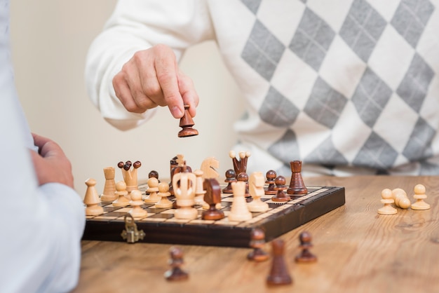 Vista cercana de la mano del padre y el tablero de ajedrez en la mesa