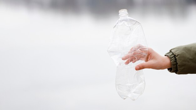 Vista cercana de la mano que sostiene la botella de plástico