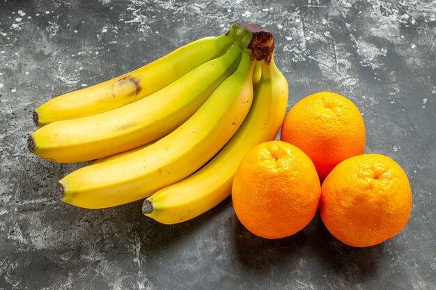 Vista cercana de naranjas frescas y plátanos orgánicos naturales paquete fondo oscuro
