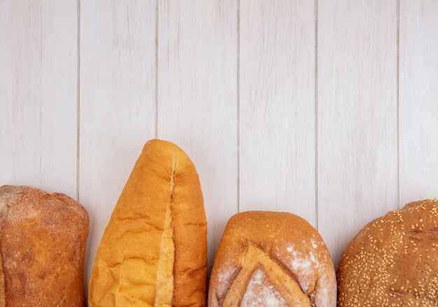 Vista cercana de panes como baguette sembrado mazorca marrón y crujientes sobre fondo de madera con espacio de copia