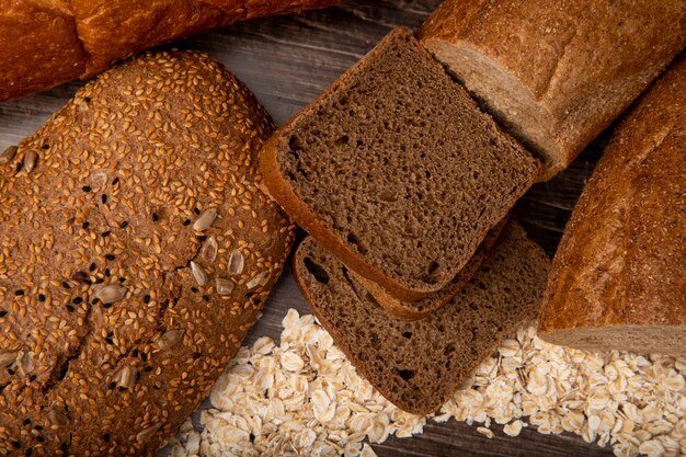 Vista cercana de panes como sándwich de pan pan de centeno pan baguette con copos de avena sobre fondo de madera