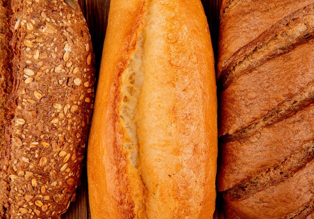 Vista cercana de panes como vietnamita y baguette con semillas negras y pan negro sobre superficie de madera