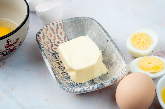 Vista cercana del plato de mantequilla con huevos sobre fondo blanco.