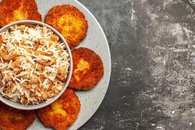 Vista cercana superior chuletas fritas con arroz cocido en rissole de carne de comida de superficie oscura