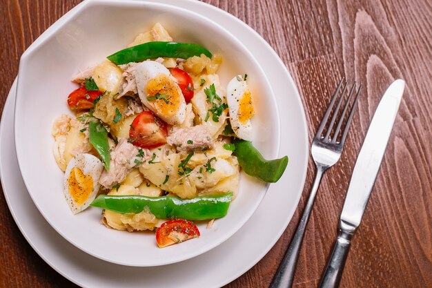 Vista cercana superior de la ensaladera italiana de papas con atún y tomate cherry